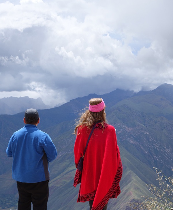 Man in blue shirt and woman in red poncho looking out the Peru's Sacred Valley